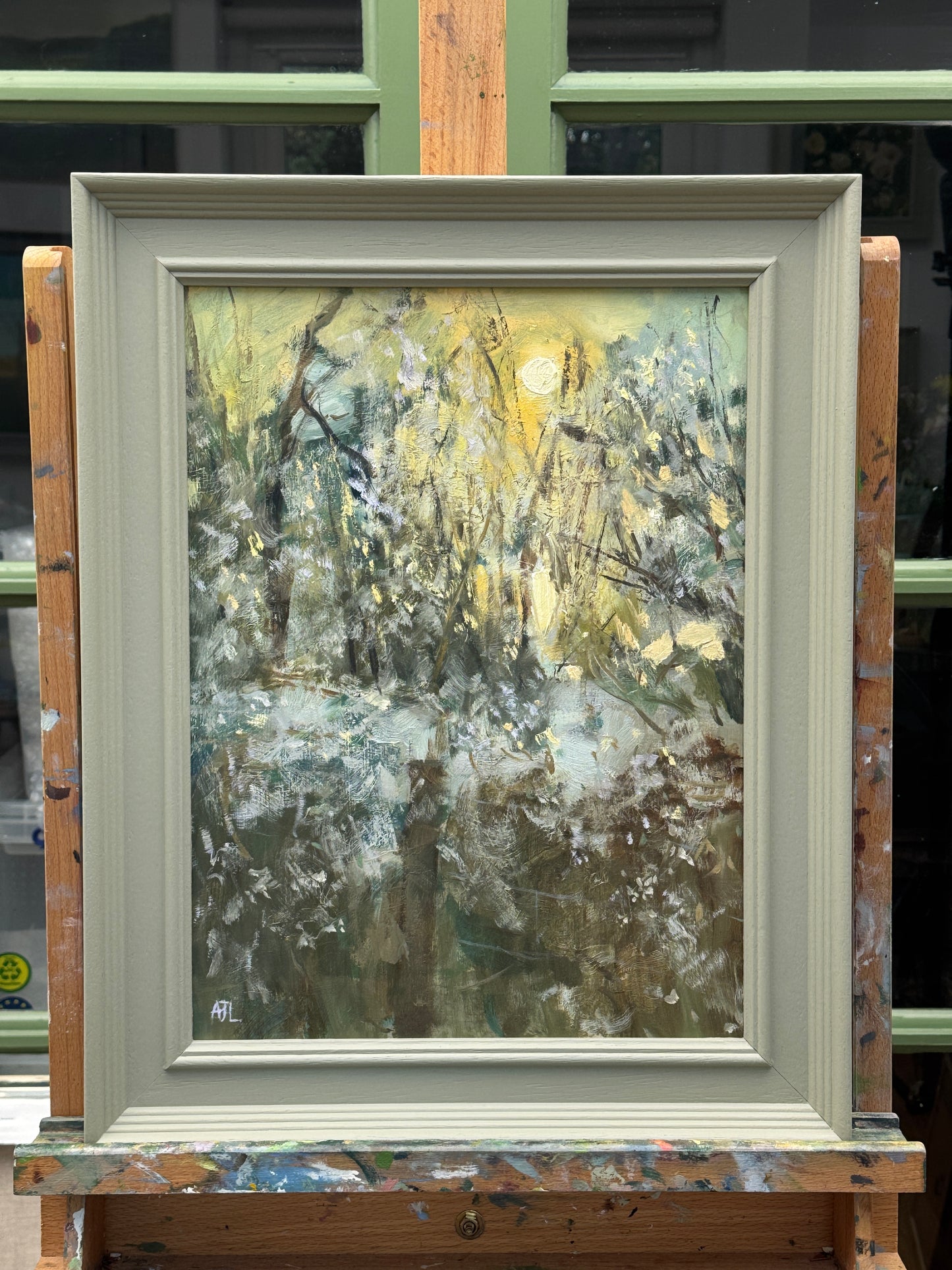 The artwork presented in a painted wooden frame on an artist easel.