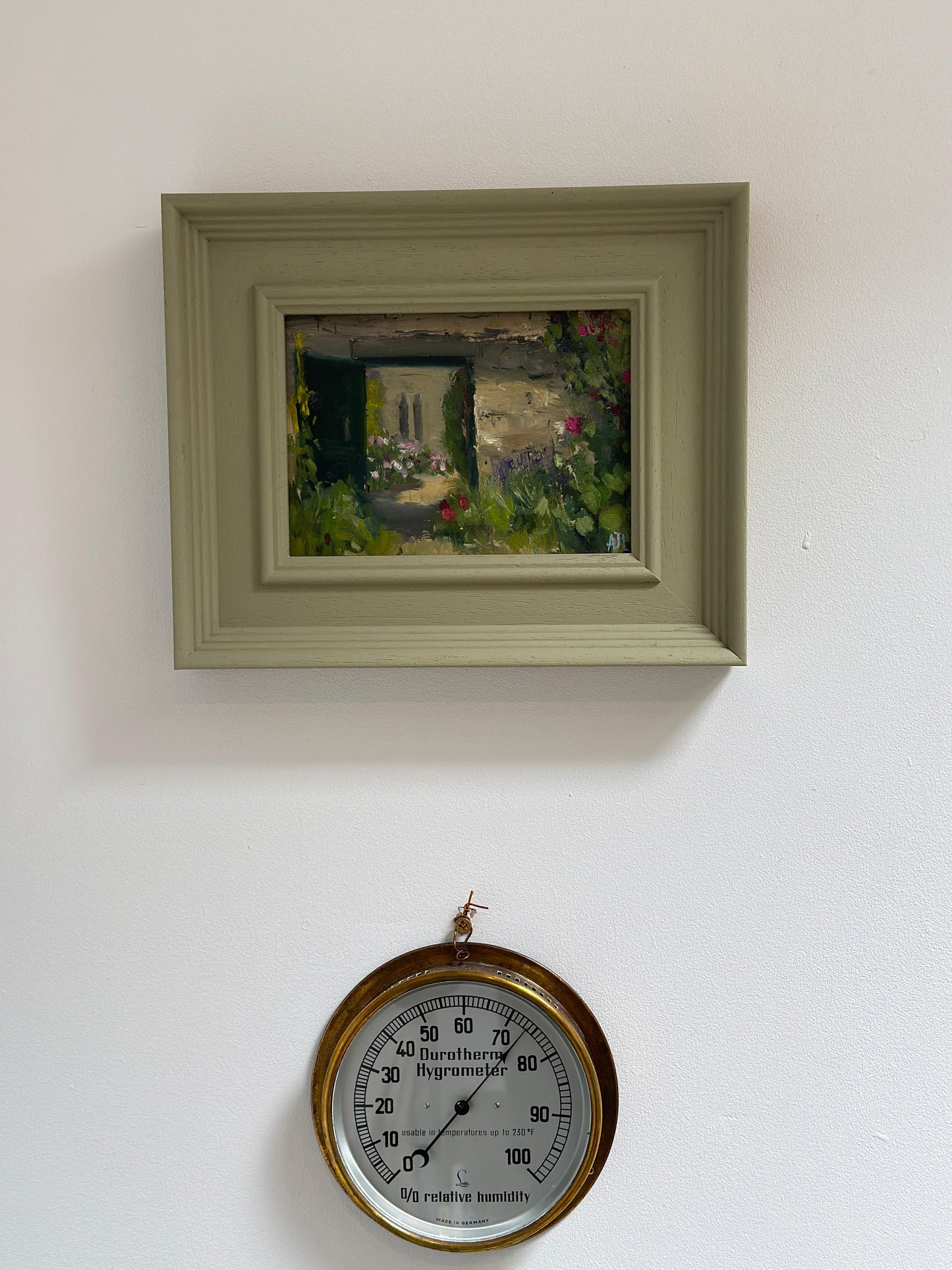 The original artwork in a green wood frame hanging on a white wall.