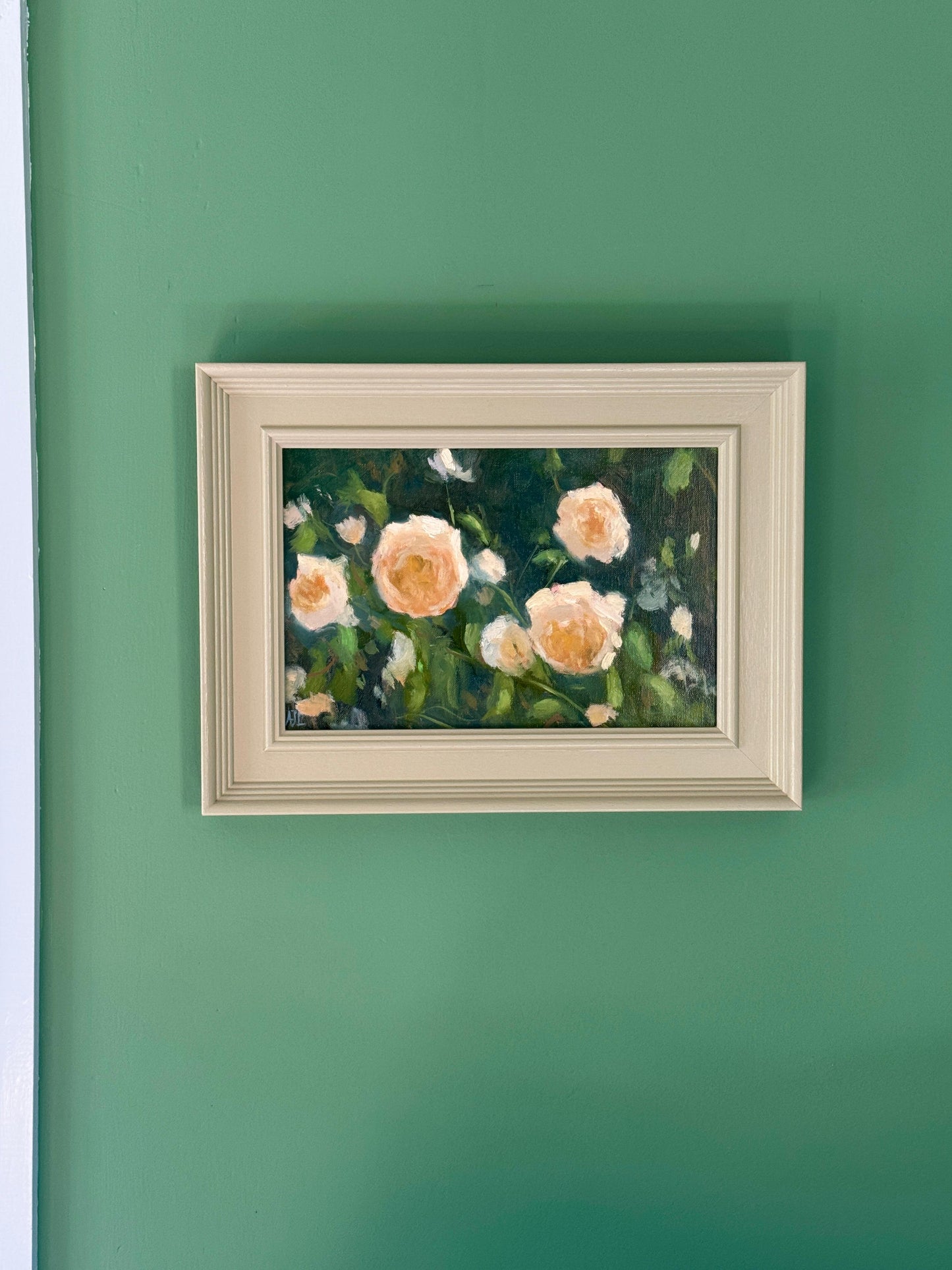 Framed painting of flowers on a green wall