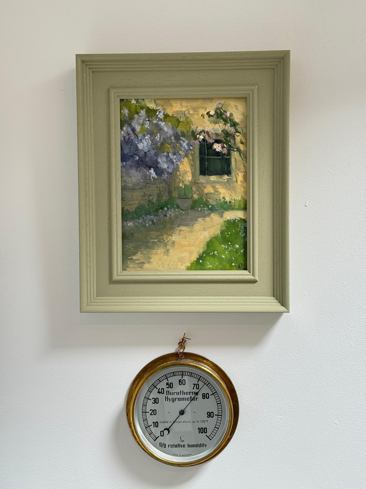 The original artwork in a green wood frame hanging on a white wall.