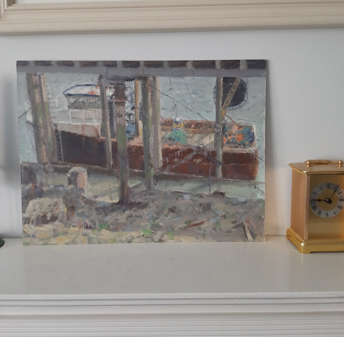 The oil painting on a fireplace ledge near a gold mantle clock.