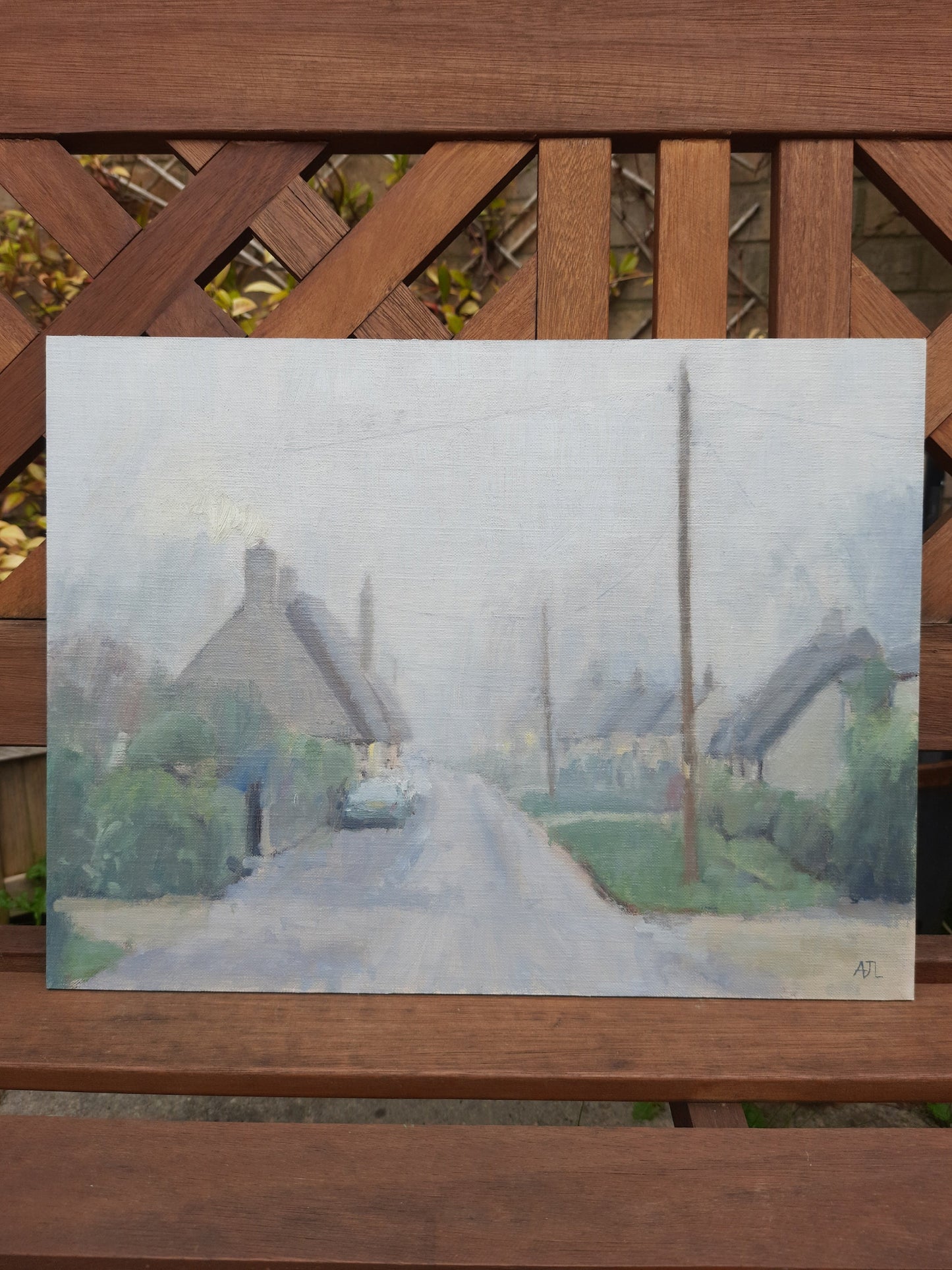 A photograph of the unframed painting on a bench outdoors.