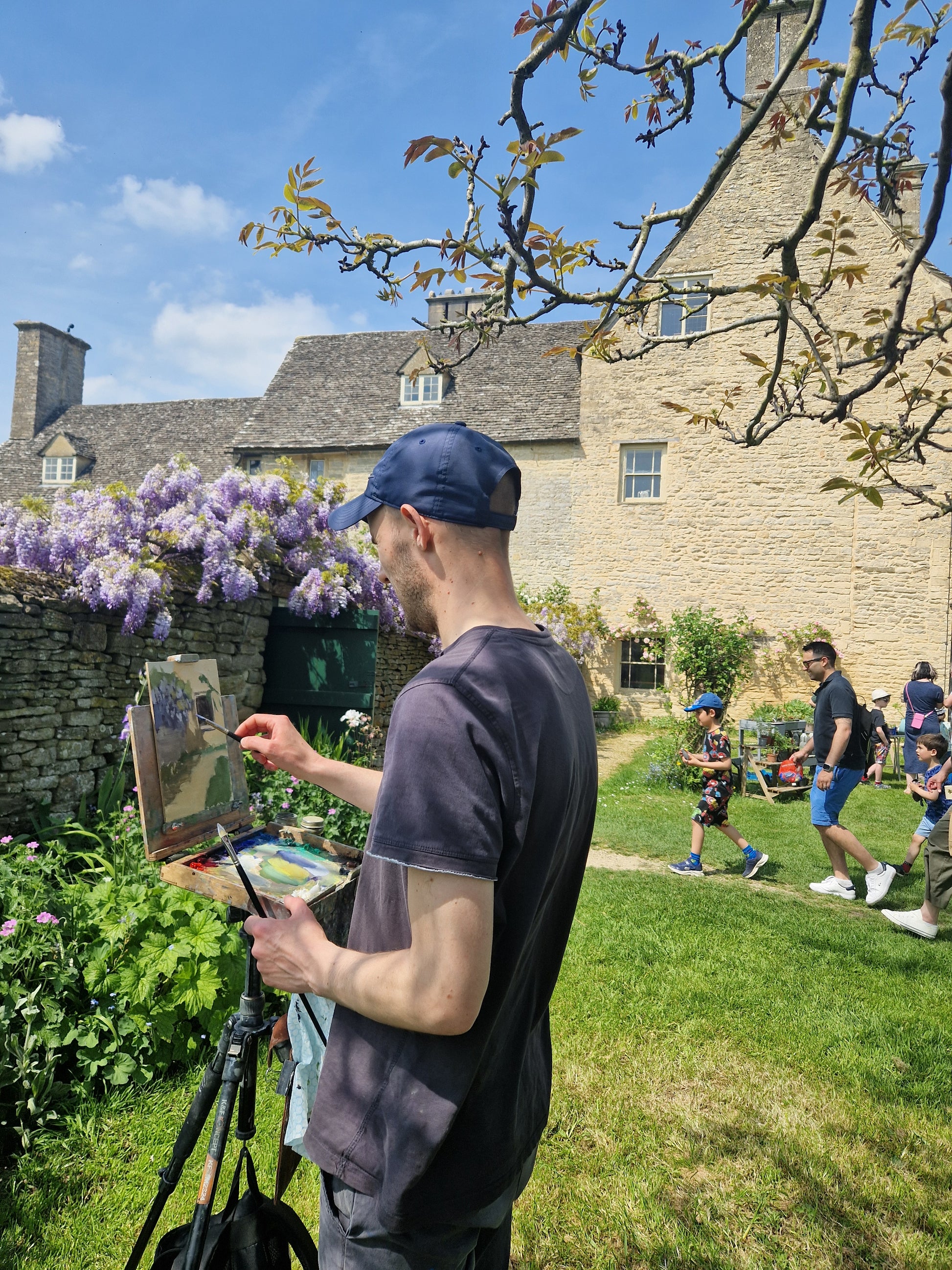 Me as I paint the scene of the artwork, with the dining room window and wisteria in the background of Cogges Manor Farm.