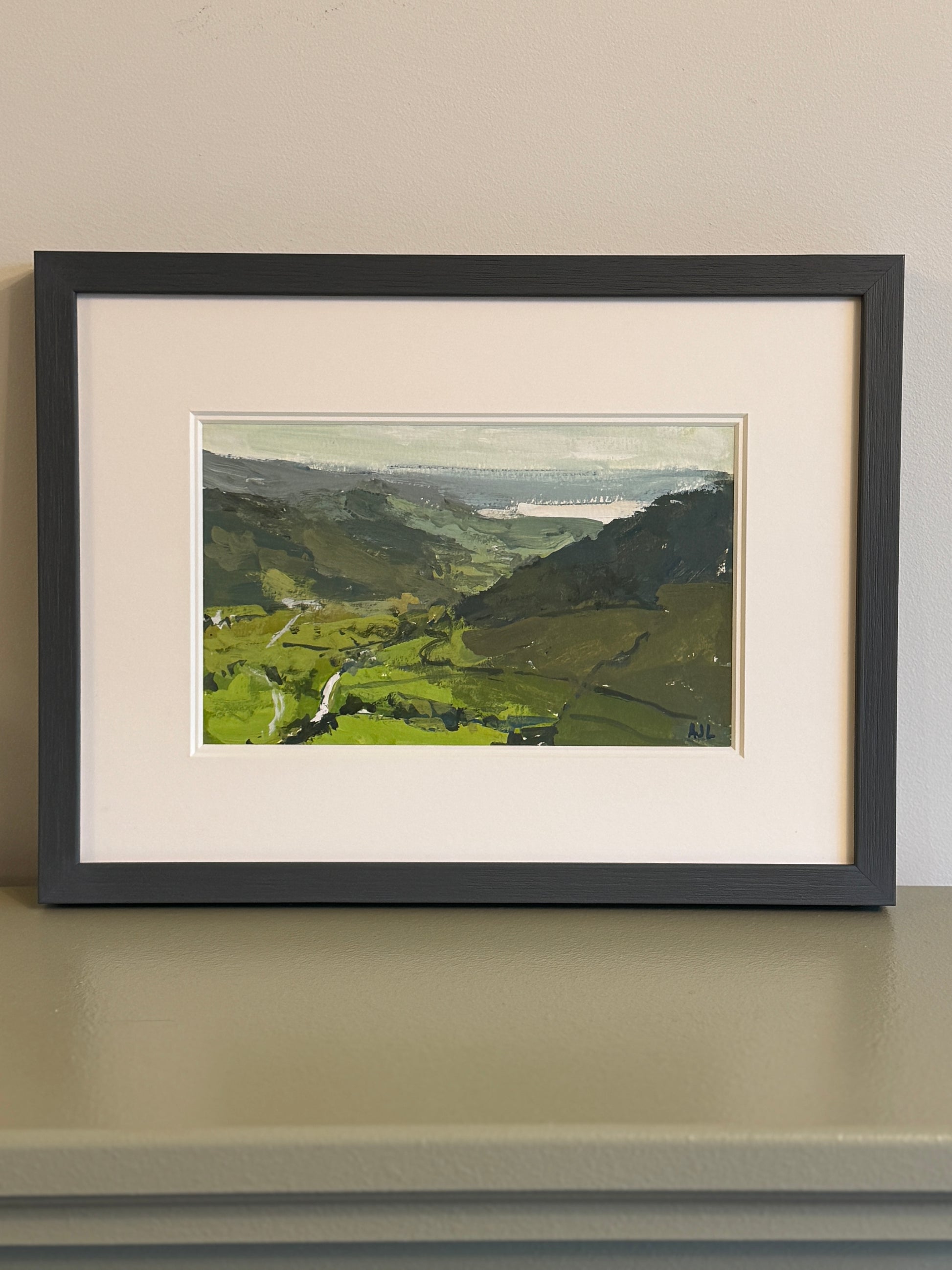 The framed painting on a mantlepiece.