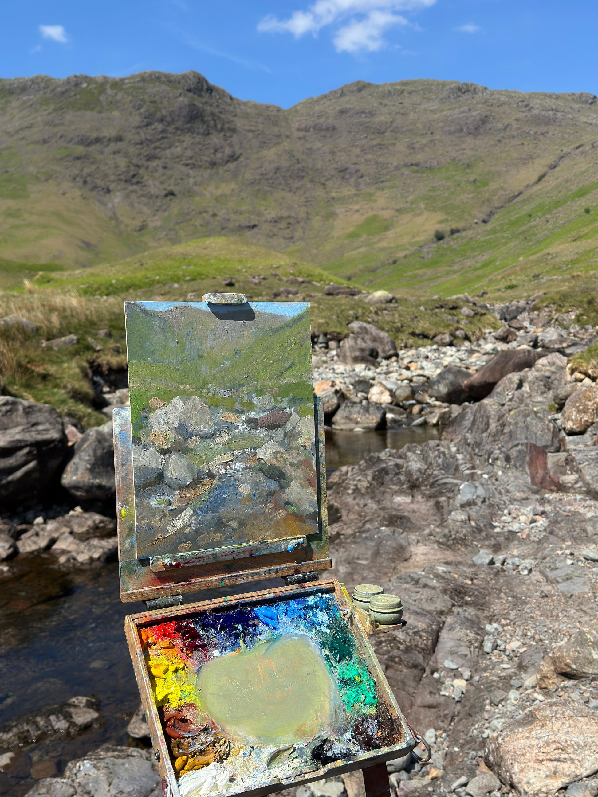 The on location oil painting on the easel with a beck and valley beyond.