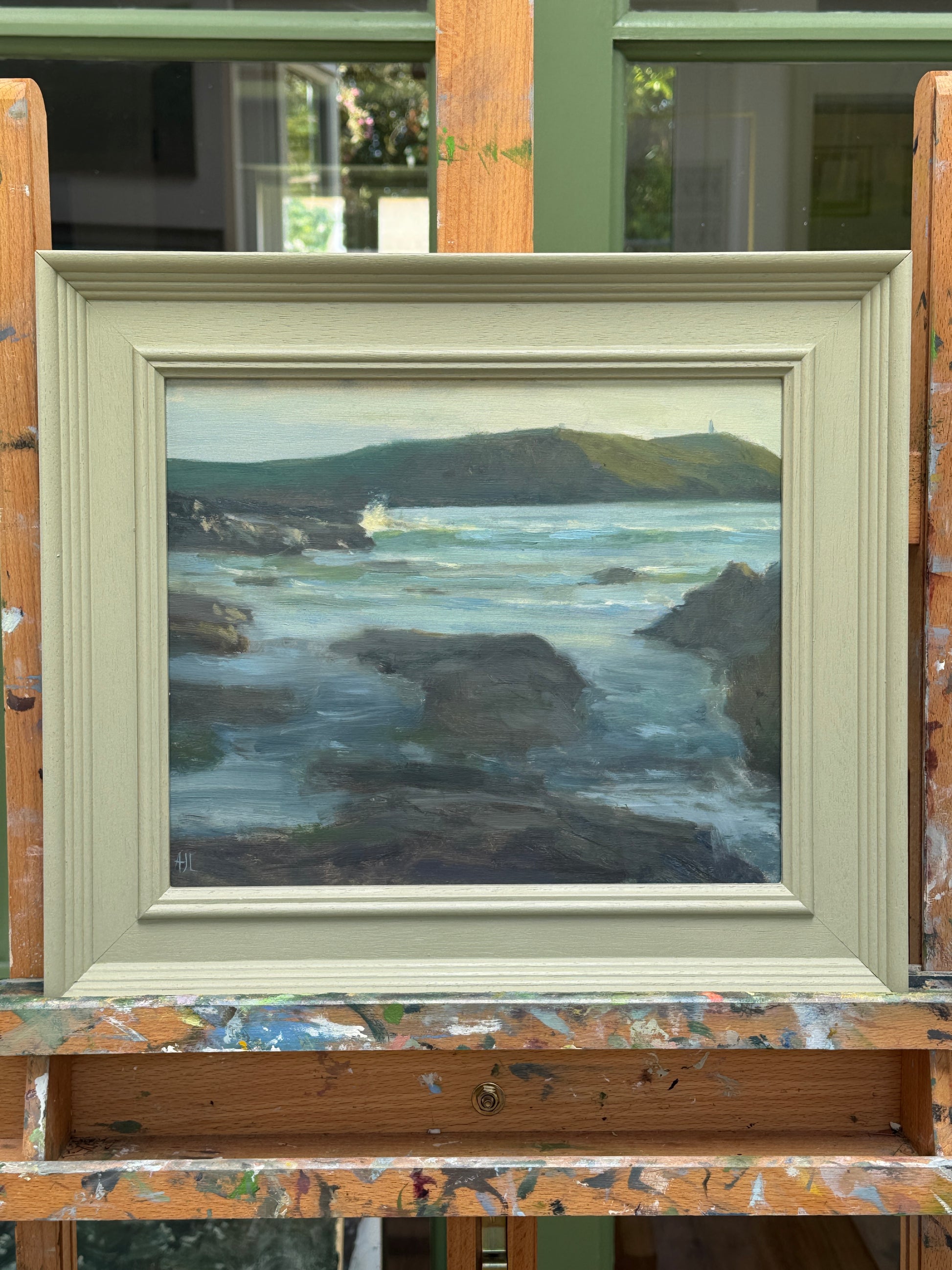 The oil painting in a wooden frame, resting on the artist easel.