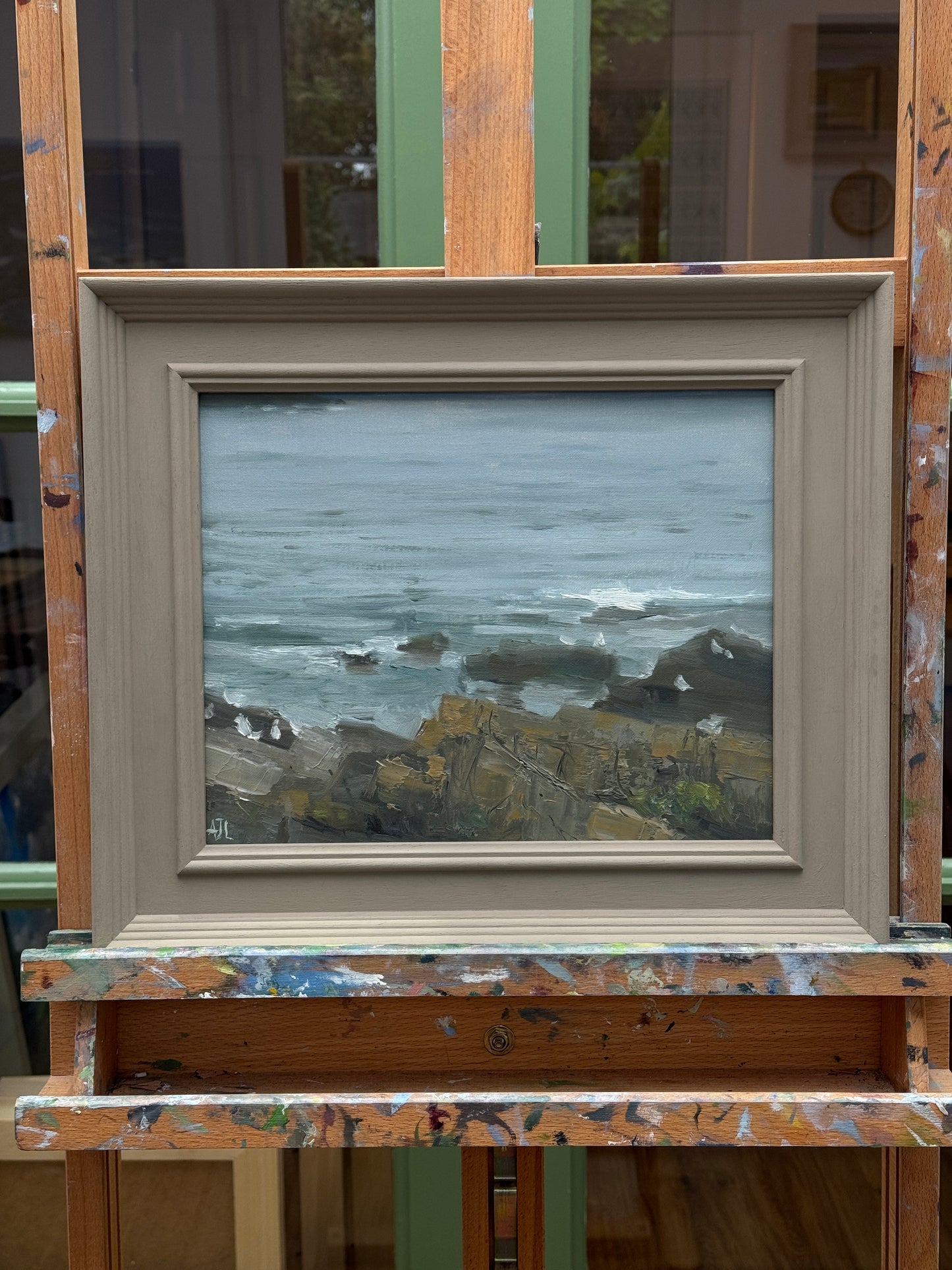 Framed artwork of a coastal scene on a wooden surface