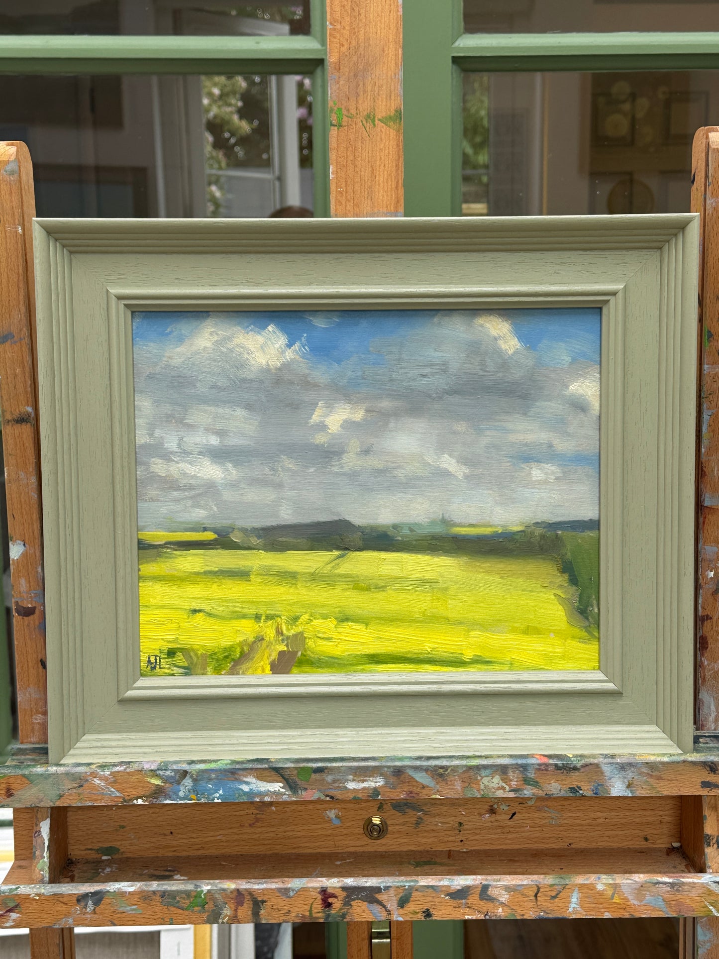 The original artwork in a wood frame on the artist easel.
