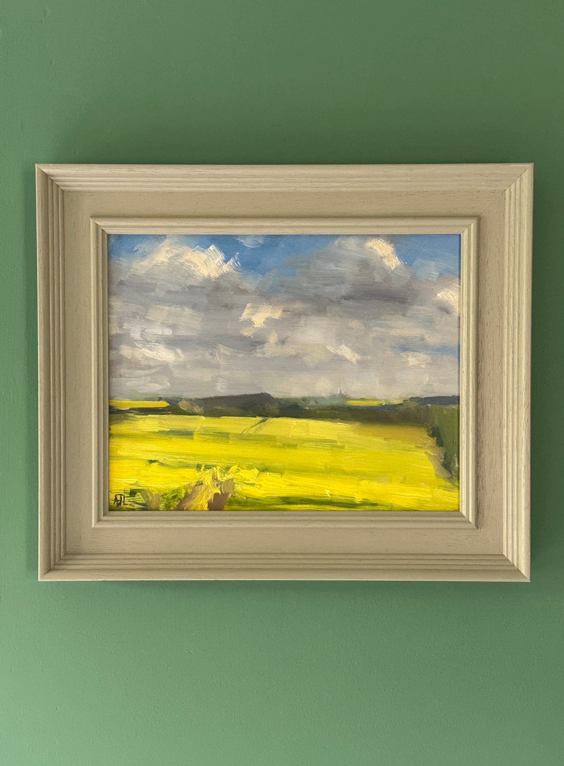 The framed oil painting hanging on a green wall.