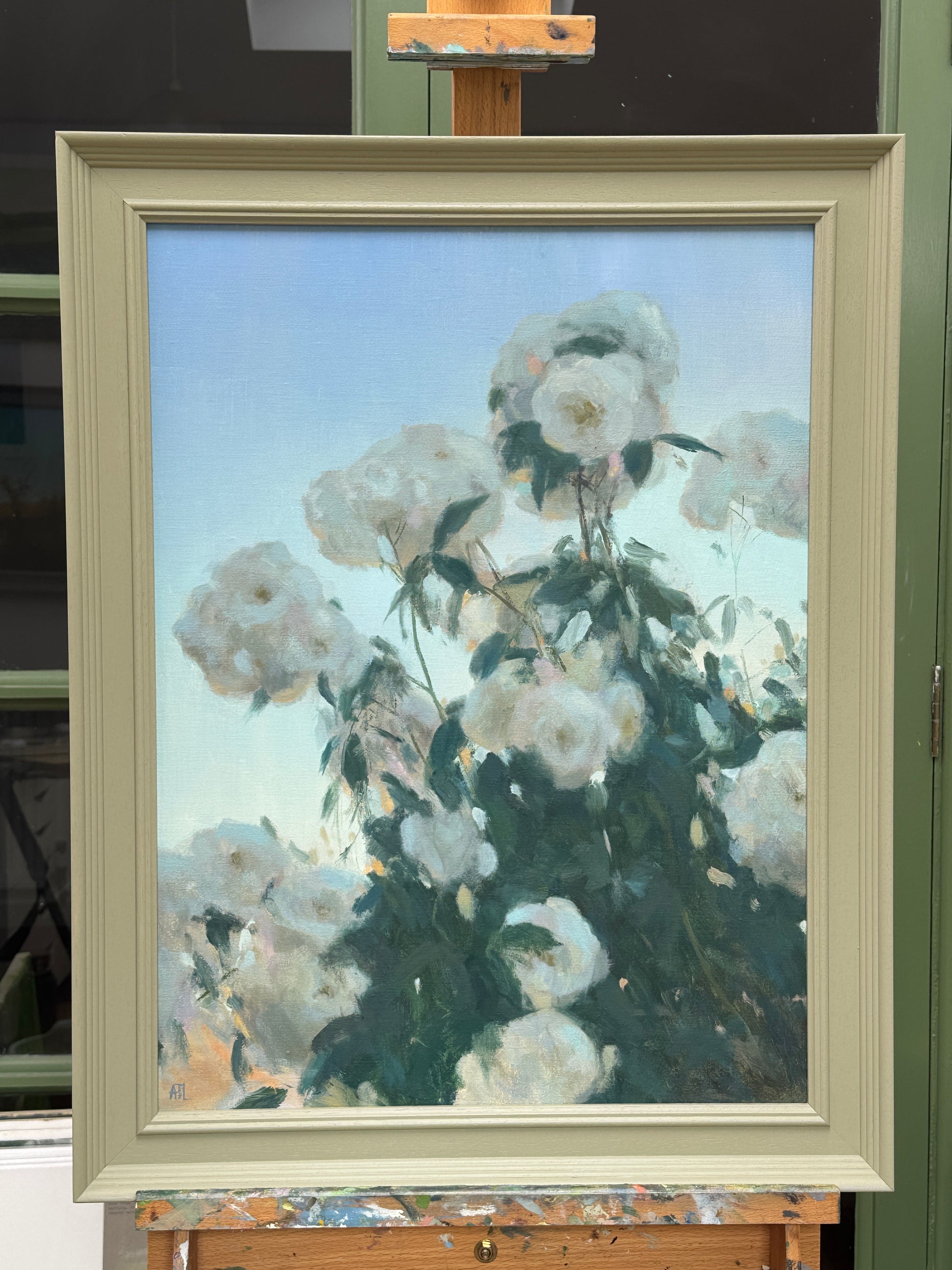 The artwork, framed and resting on an artist easel.