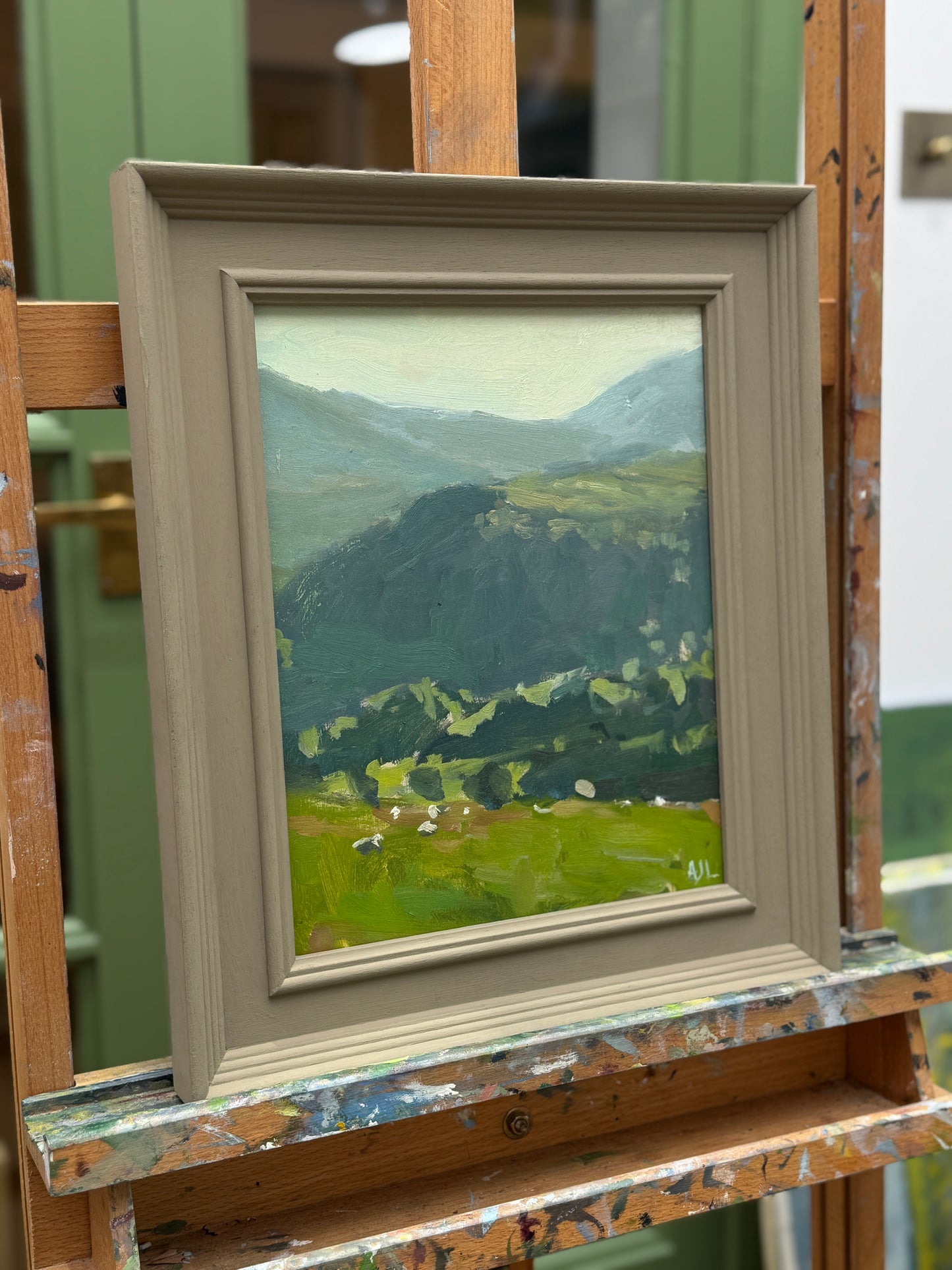 The framed painting on an easel as seen from the side.