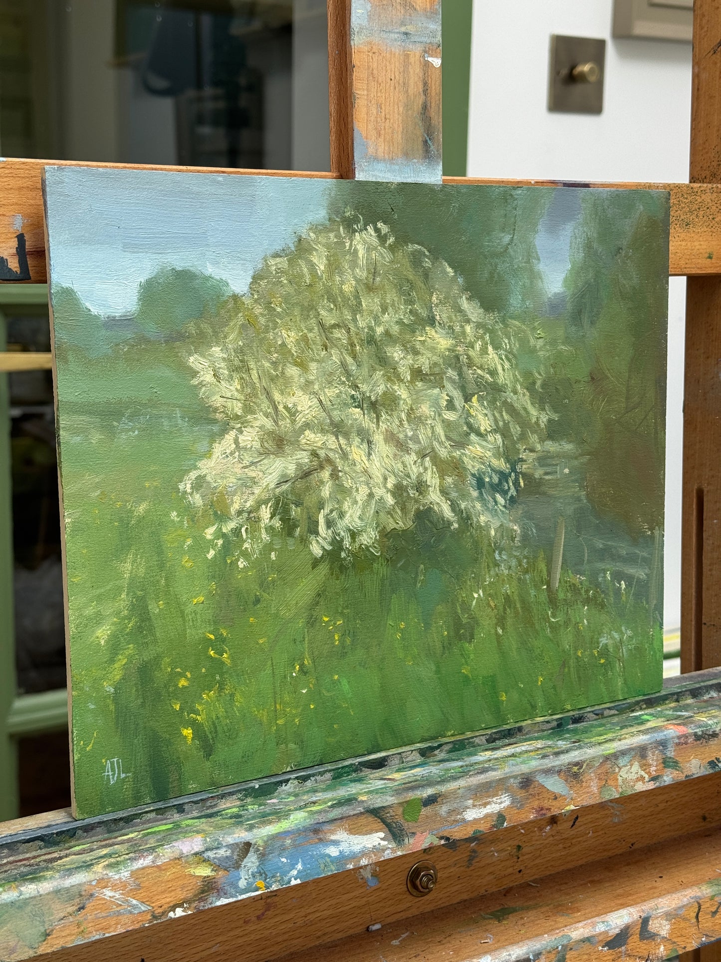 The oil painting on the artist easel, photographed from the side.