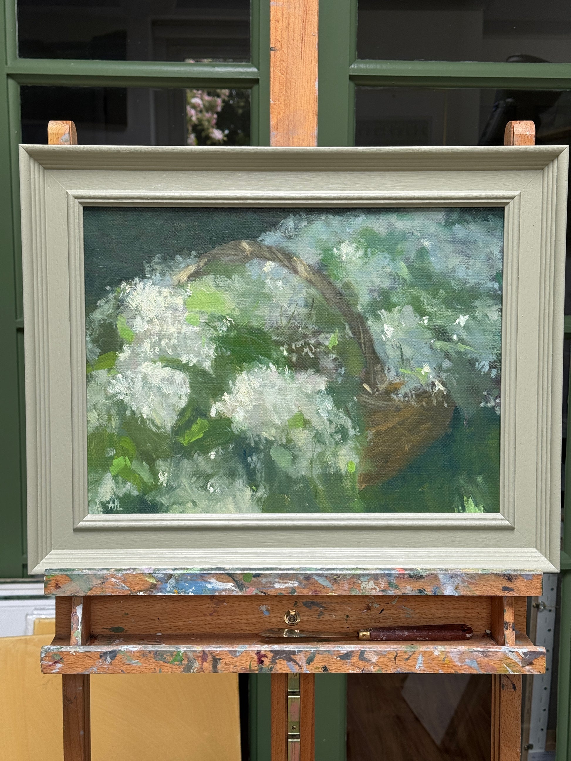 The painting, framed and resting on the artist easel.