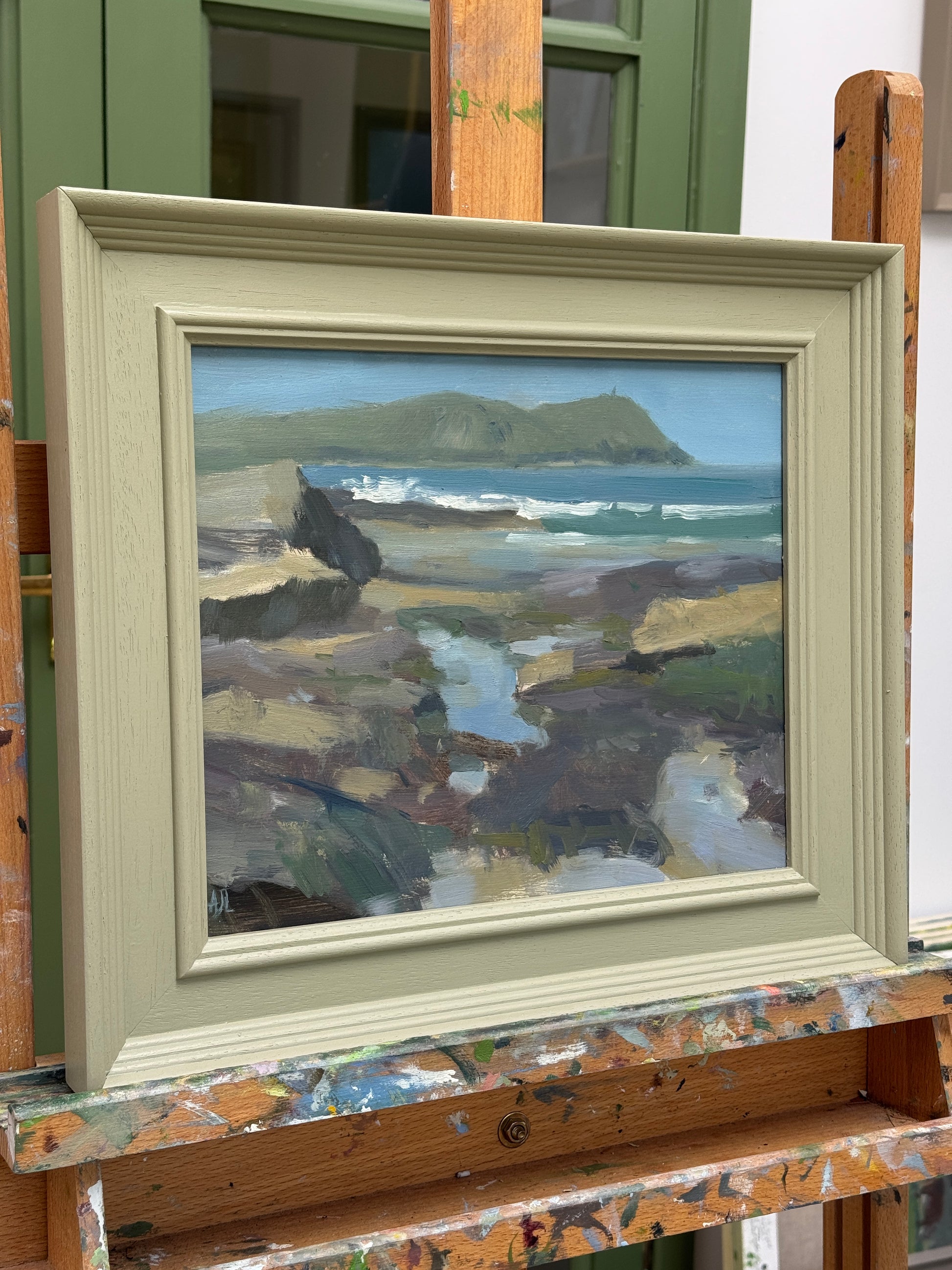 The framed artwork photographed from the side, resting on the artist easel.