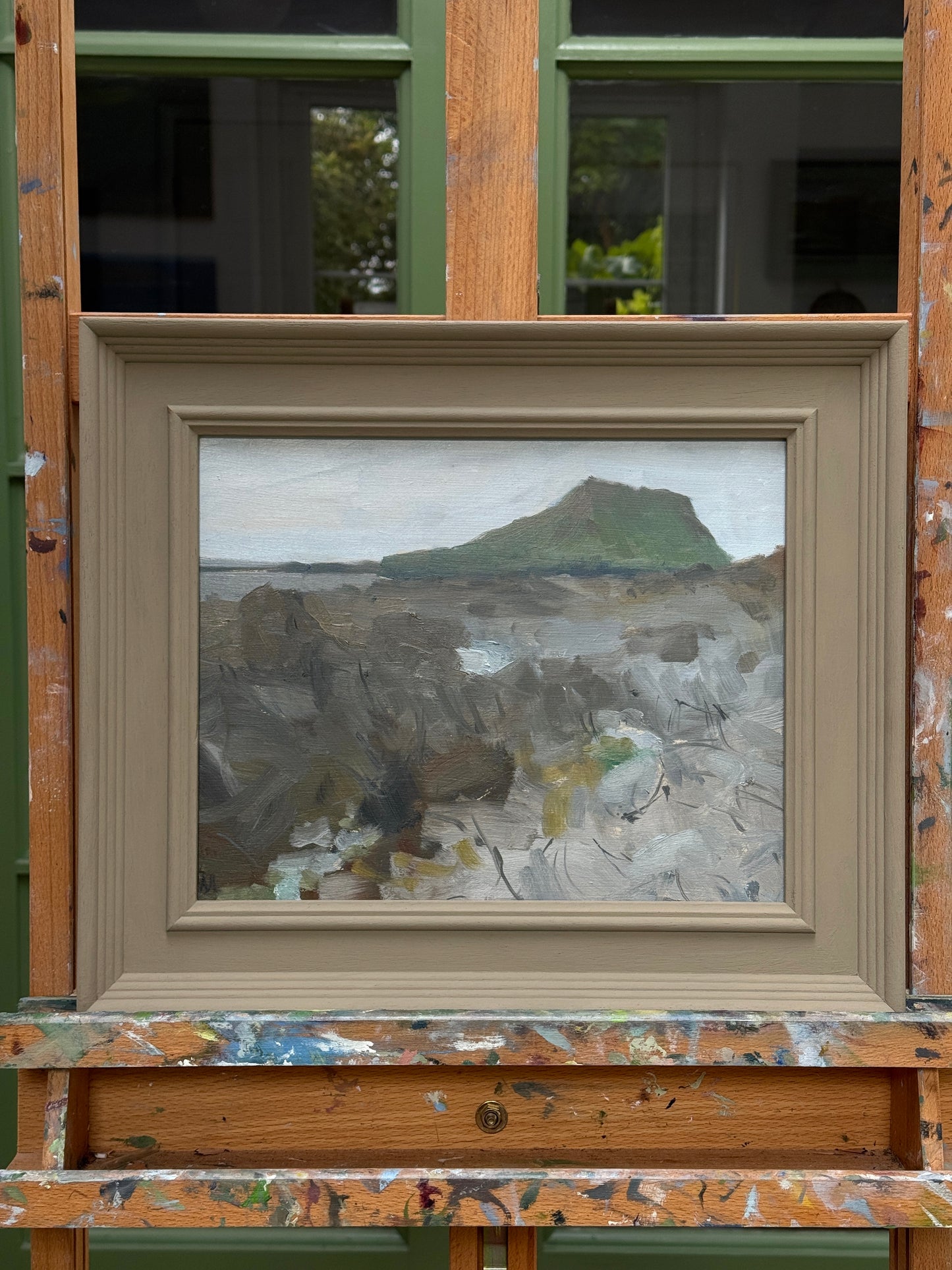 The painting in a wooden frame on an easel.