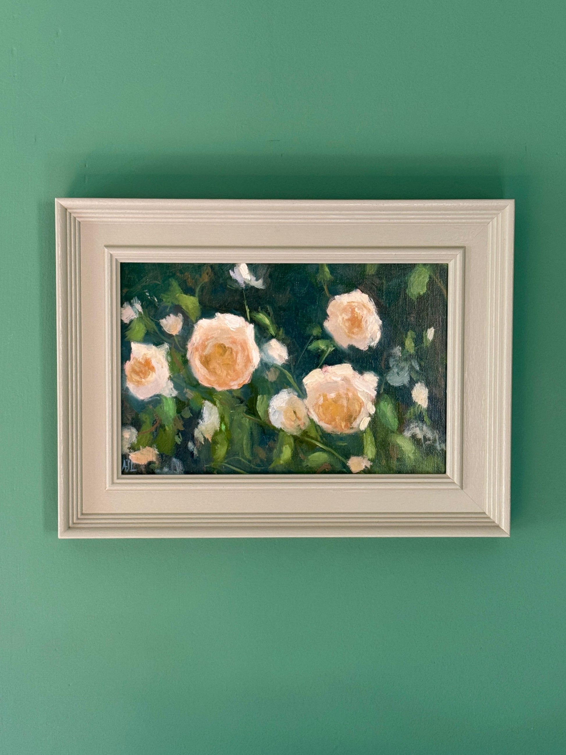Framed oil painting of flowers on a green wall