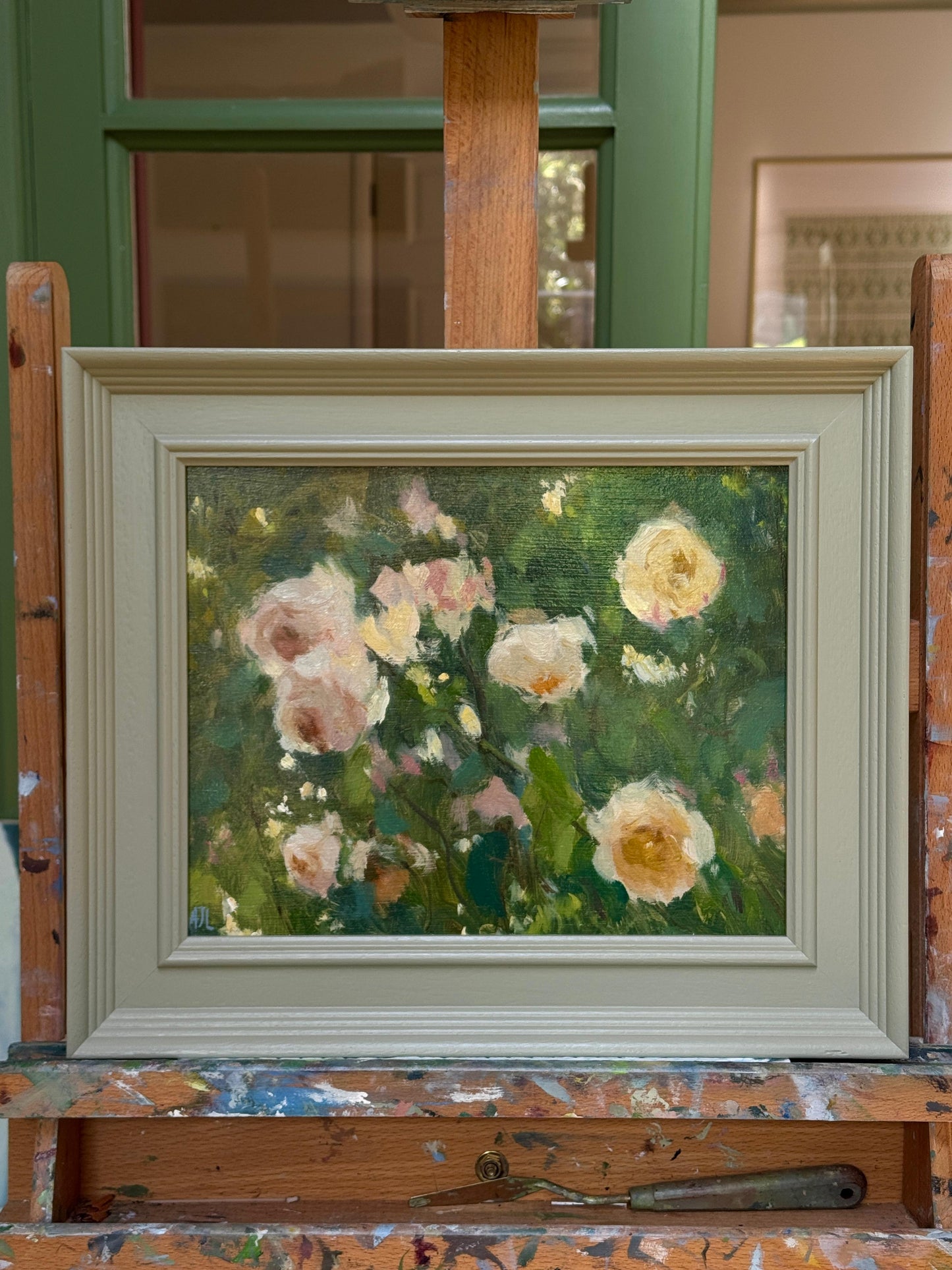 Framed painting of roses on an easel with a green background