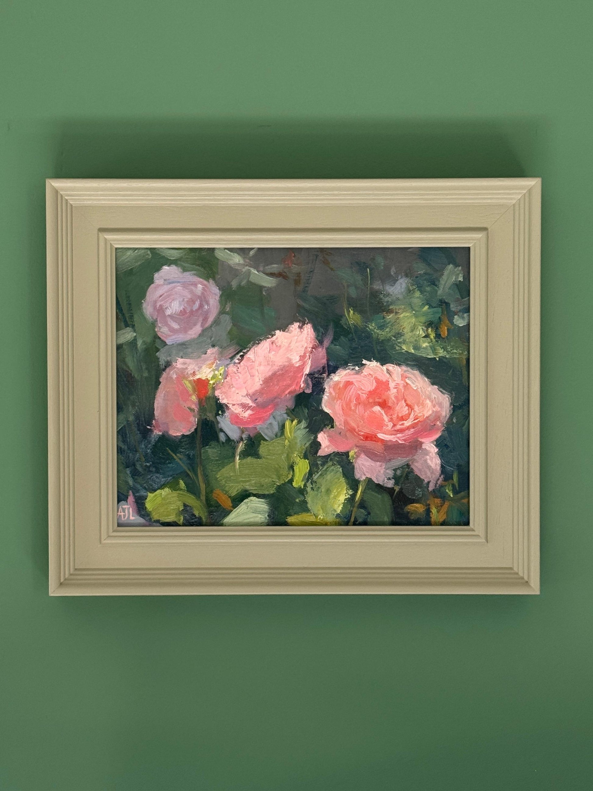 Framed painting of pink roses on a green wall.
