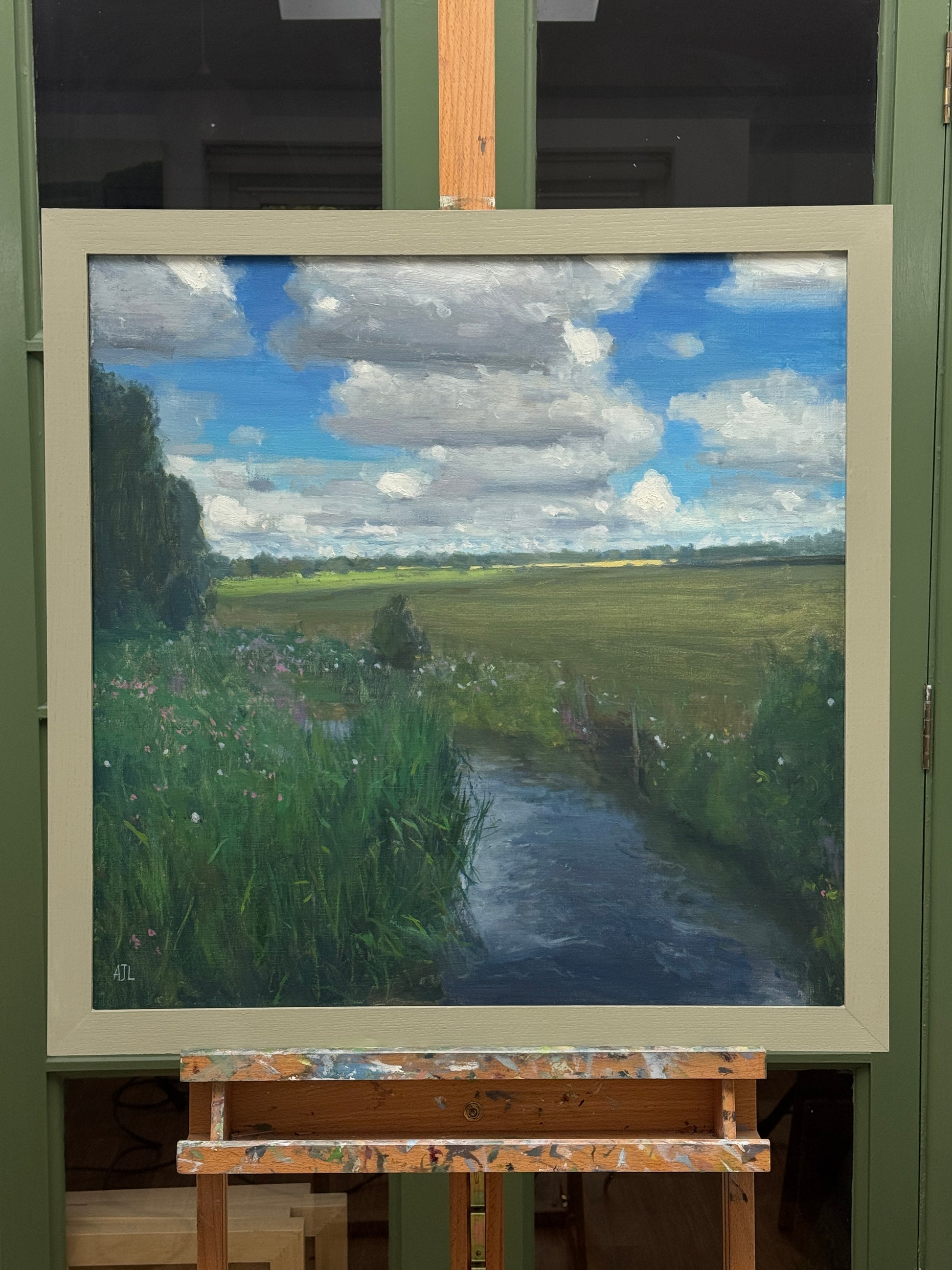 The painting, framed, on an easel.