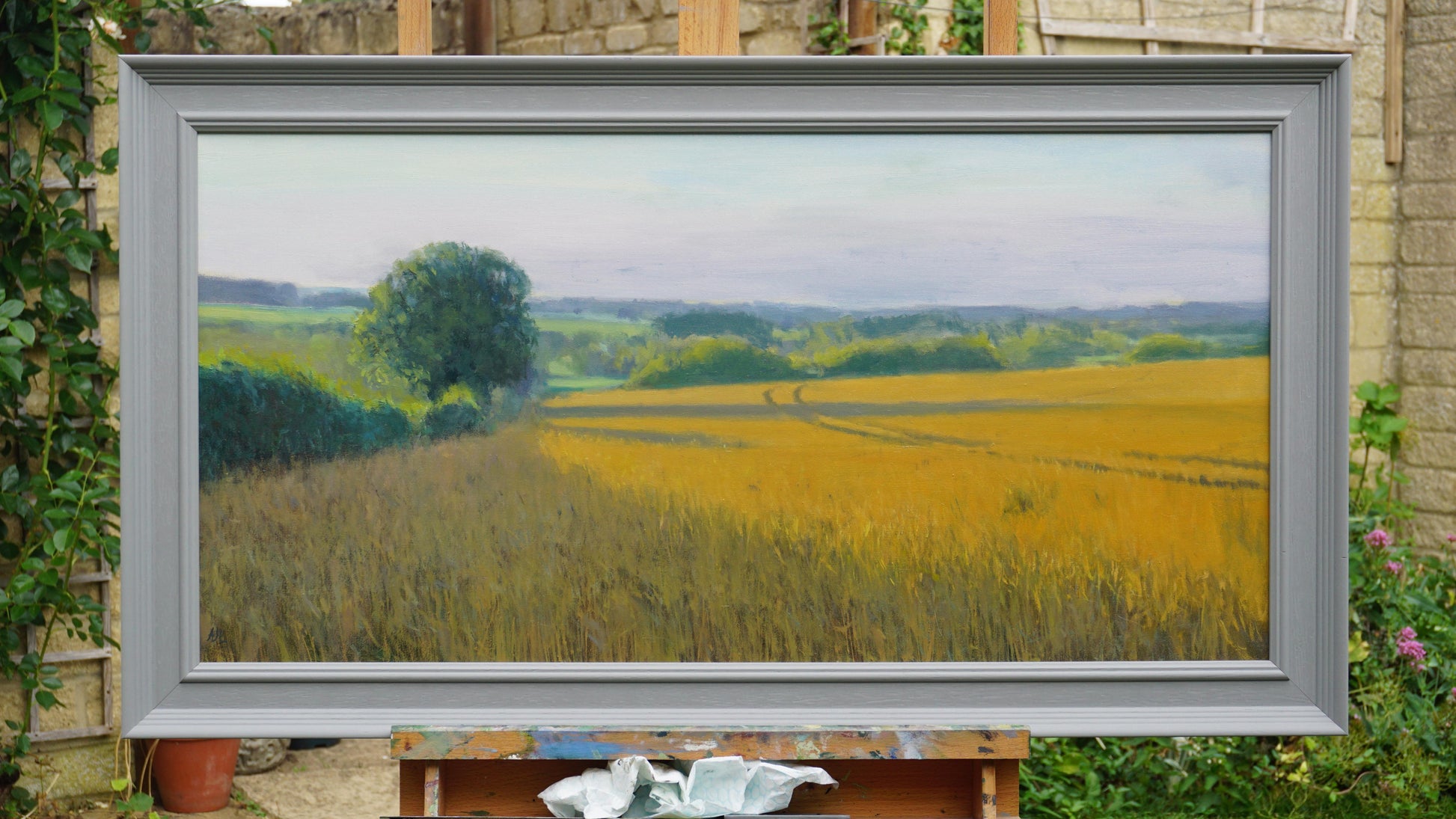 The original artwork in a grey wood frame on an easel.