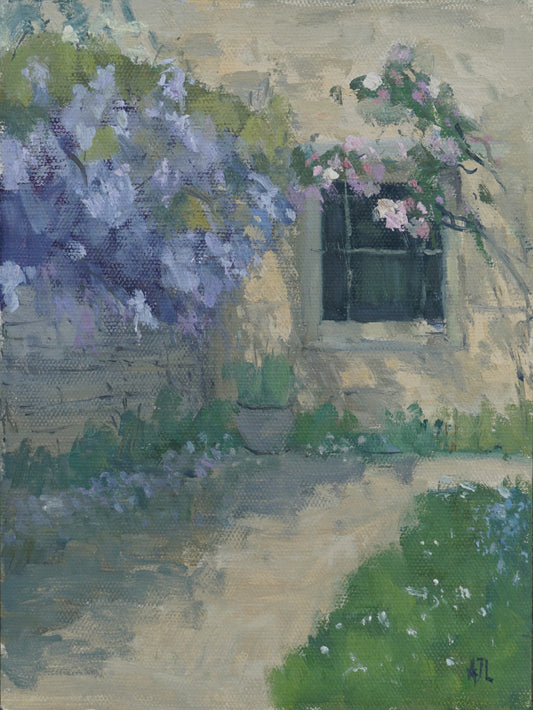 An original oil painting of the exterior of Cogges Manor Farm by the dining room window, with the wall to the garden covered in blooming purple wisteria, and dappled sunlight falling upon the path nearby. The artist has signed AJL, for "Alex James Long", at the bottom right of the artwork. 