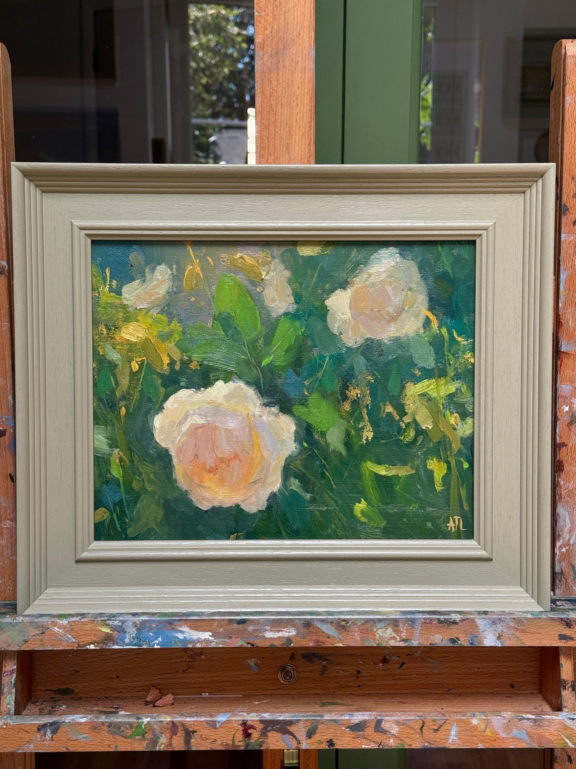 Framed painting of flowers on a wooden easel.
