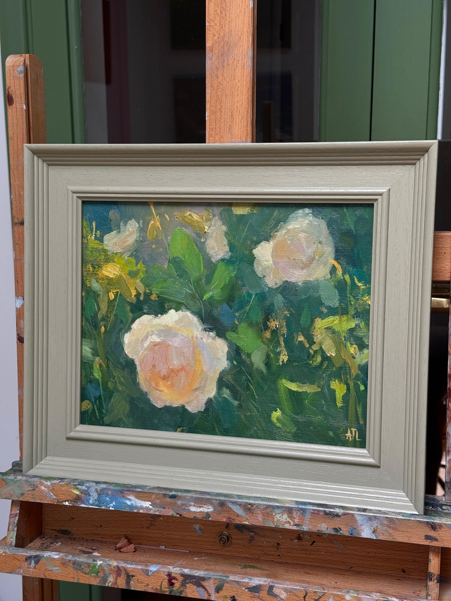 Framed painting of flowers on a wooden easel seen from the side.